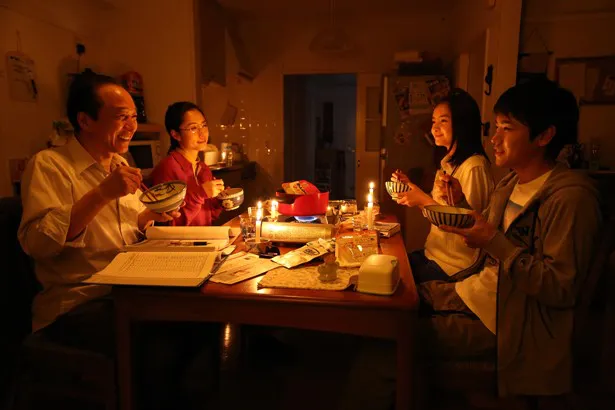 電気がなくなり、ローソクを使って食事をする鈴木家の父(小日向文世)、母(深津絵里)、結衣(葵)、賢治(泉澤祐希)(写真左から)