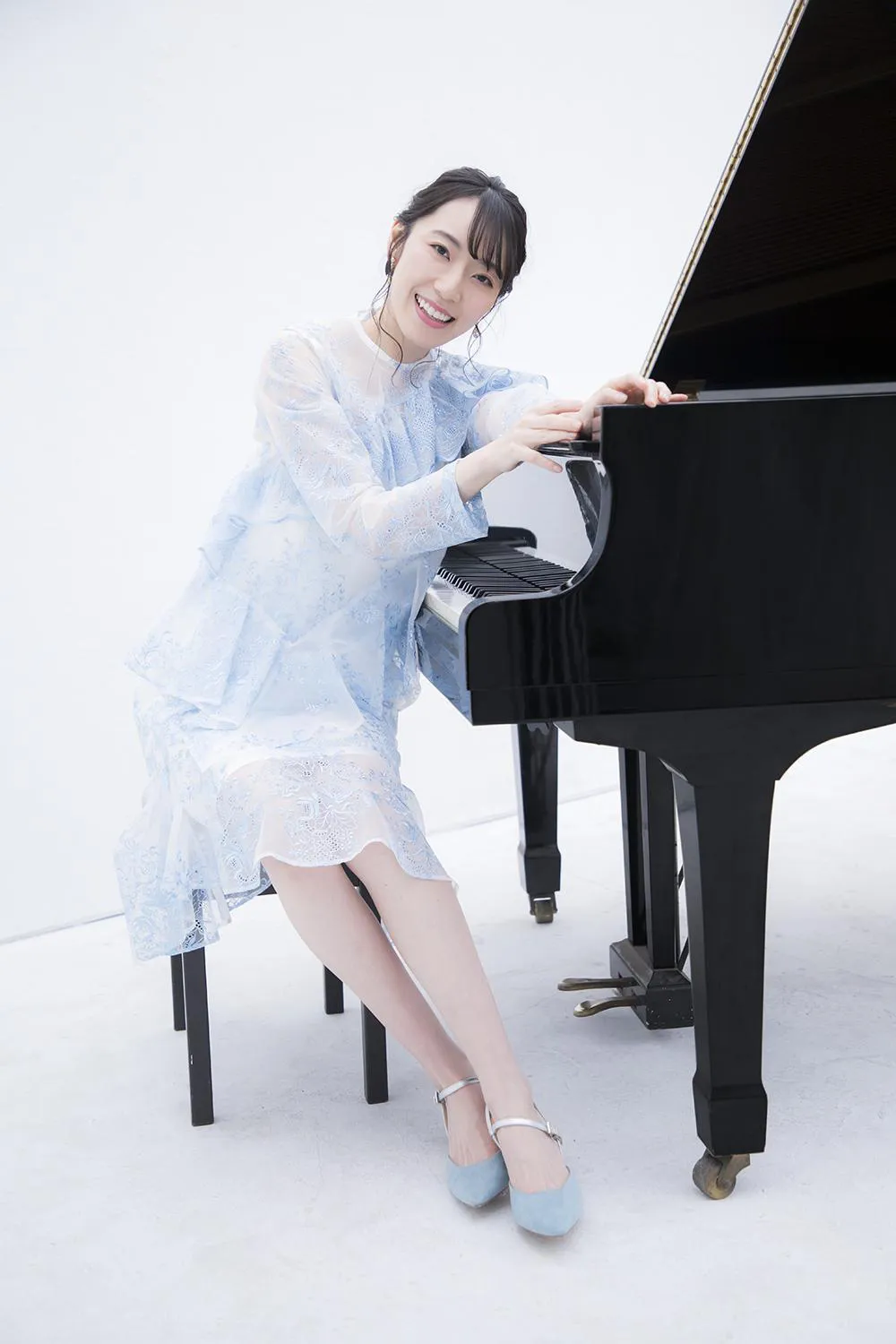 ピアノの前で水色の透け感のあるドレス姿の松井咲子