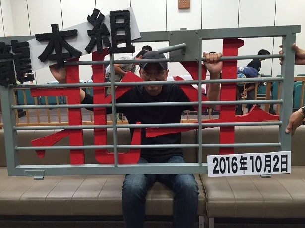 北斗が収監された拘置所の鉄格子で作られたパネルを持ち、記念撮影する瀧本智行監督
