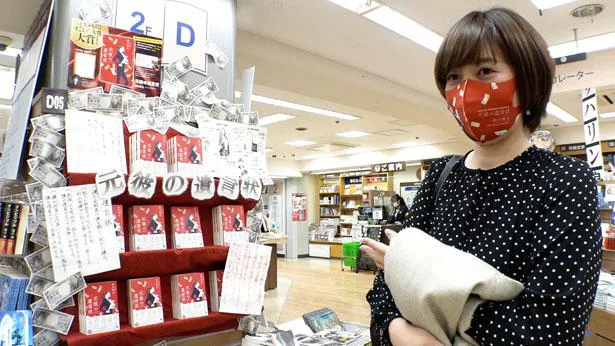 【写真を見る】書店で「元彼の遺言状」が陳列された棚の前に立つ新川帆立