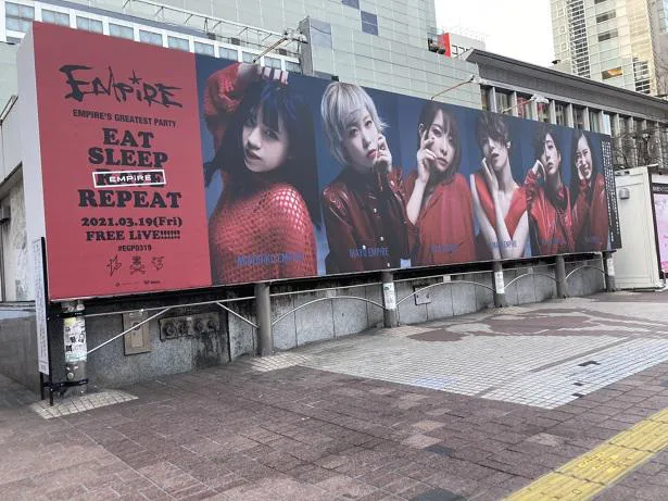【写真を見る】EMPiREのフリーライブの開催は渋谷駅ハチ公交差点前の巨大広告にて発表