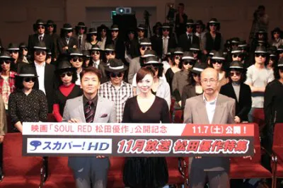 松田優作の仮装をしたファンと記念撮影した、くりぃむしちゅー・上田晋也、松田美由紀、丸山昇一（左から）