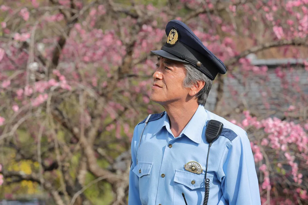 【写真を見る】桜をバックに優しい表情を浮かべる“駐在さん”こと江波敦史(寺島進)