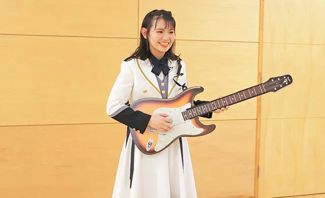 ギターの形をしたクラッカーを持つ峯吉愛梨沙