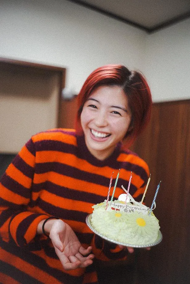 【写真を見る】奈緒のバースデーケーキを笑顔で運ぶ佐久間由衣