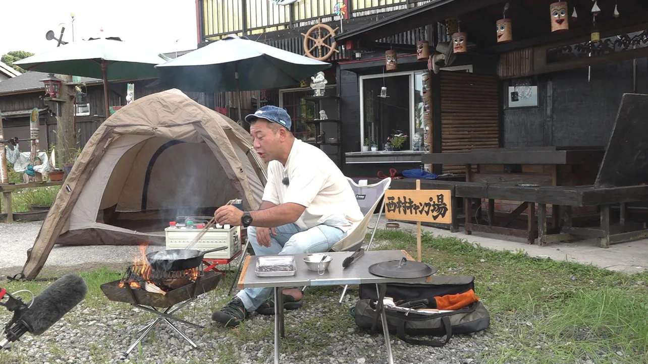 【写真をみる】大量のトーテムポールに囲まれたキャンプ地でキャンプ飯披露