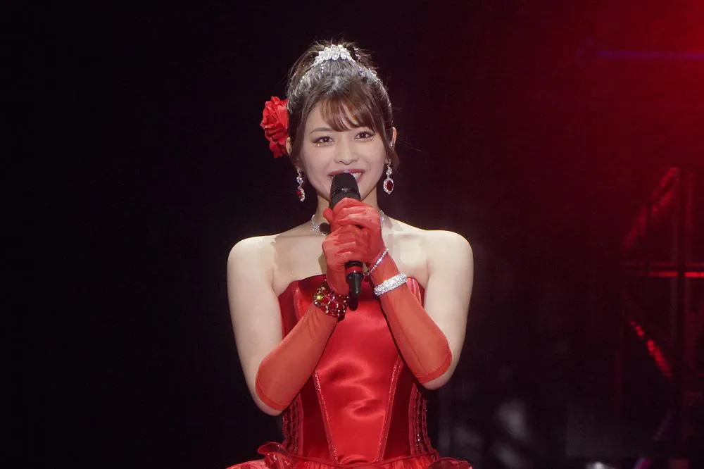 ファンへメッセージを送る赤いドレス姿の金澤朋子
