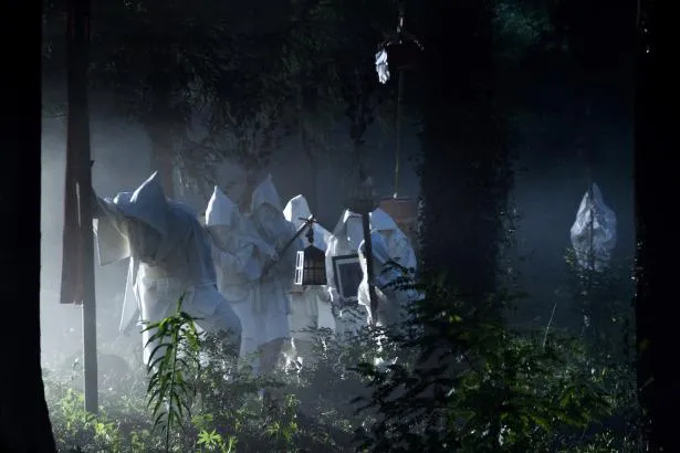 【写真】森の中を歩く白装束をまとった村人たち