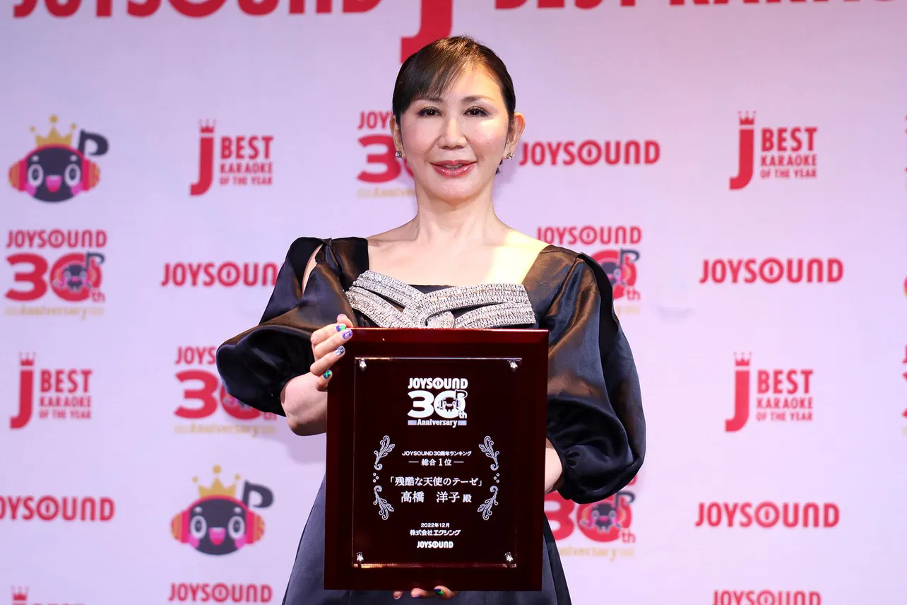 「JOYSOUND30周年ランキング」総合1位の盾を持って撮影に応じる高橋洋子