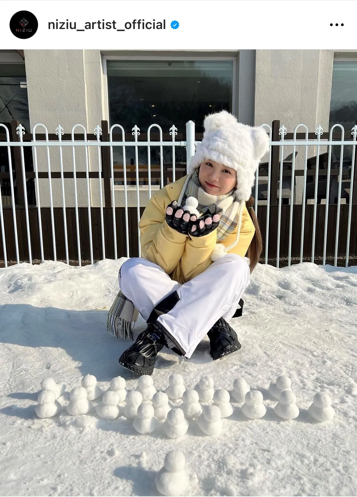 真っ白な雪の上で雪だるまを並べてほほ笑むNiziU・リオ