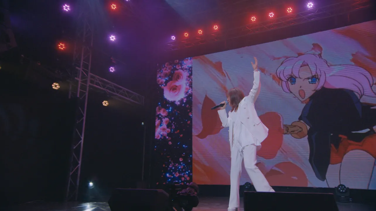 【写真】「少女革命ウテナ」のアニメの映像が流れる巨大スクリーンの前で歌う奥井雅美