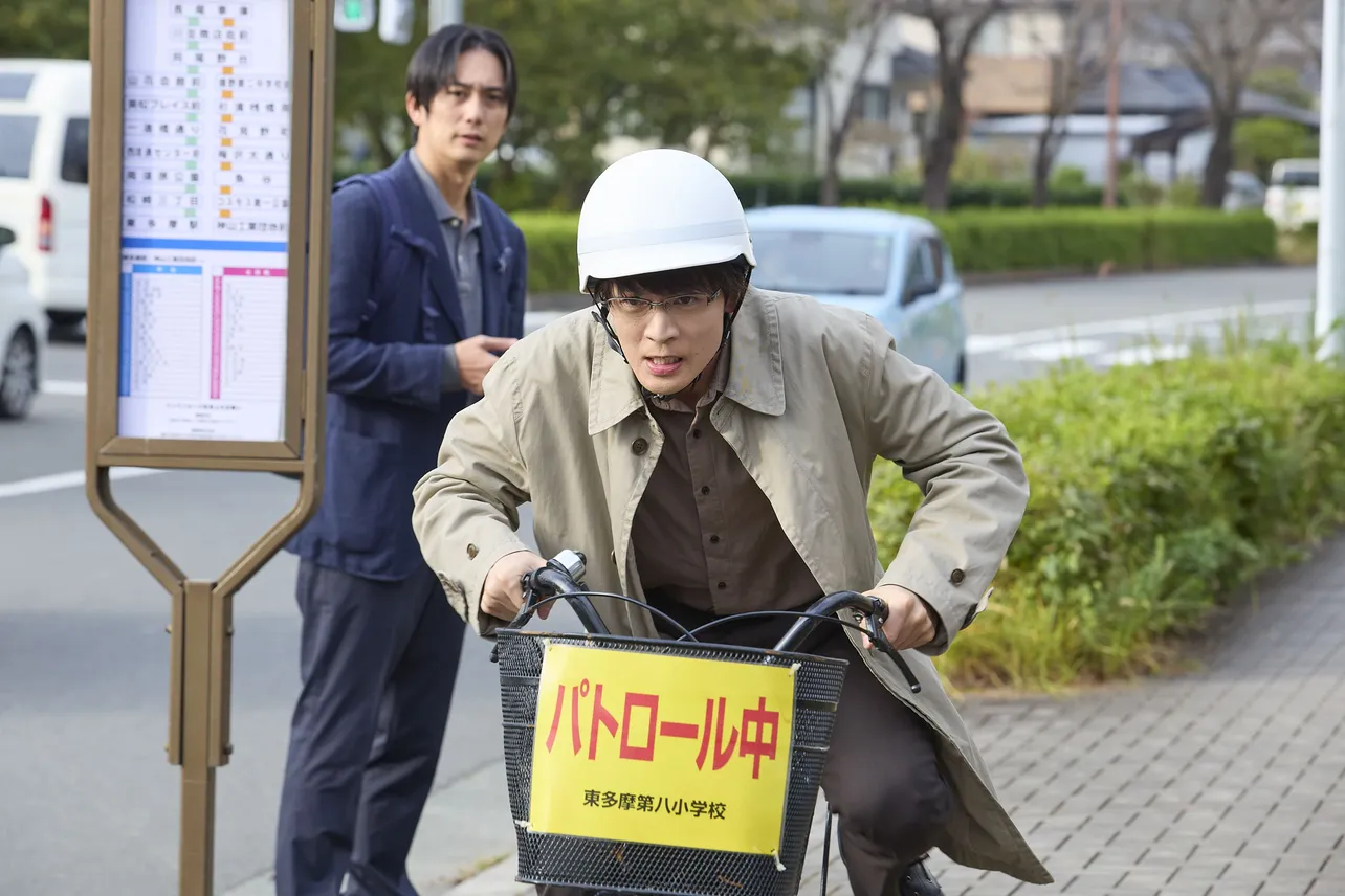 【写真】ヘルメットを被り、「パトロール中」のラベルを下げた自転車をこぐ牧野(松下洸平)