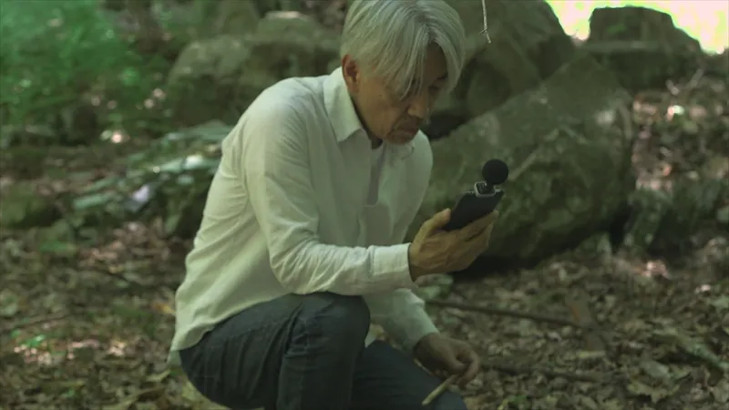 【写真を見る】自然の中で環境音を収集する坂本龍一