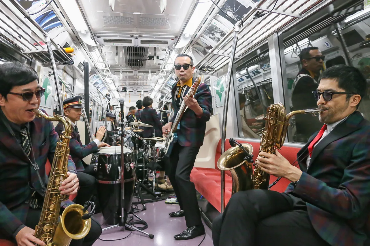 【写真を見る】地下鉄の車内というシチュエーションだけあって、谷中敦(右)やGAMO(左)は座席に座って演奏する場面も！