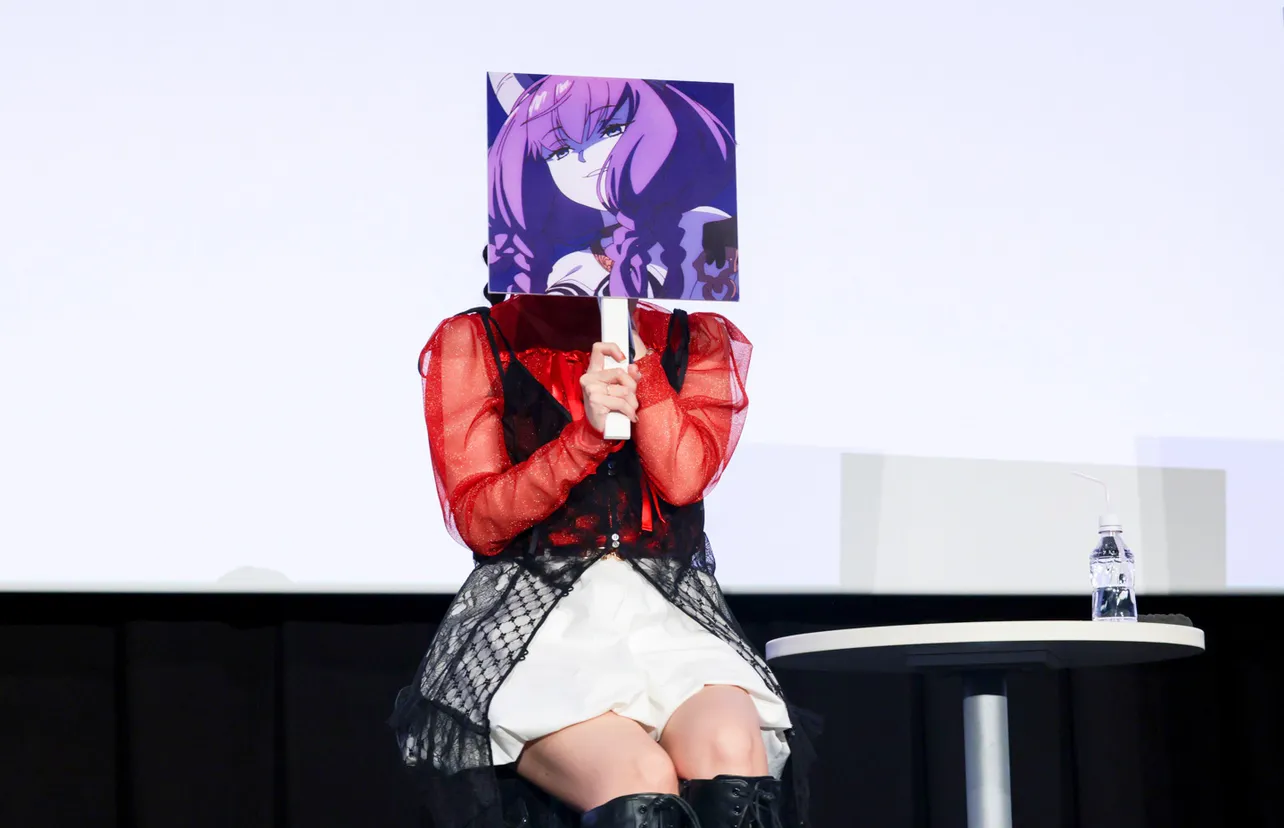 【写真】アウラの手持ちパネルで顔を隠し、アウラになりきって生でせりふを披露する竹達彩奈