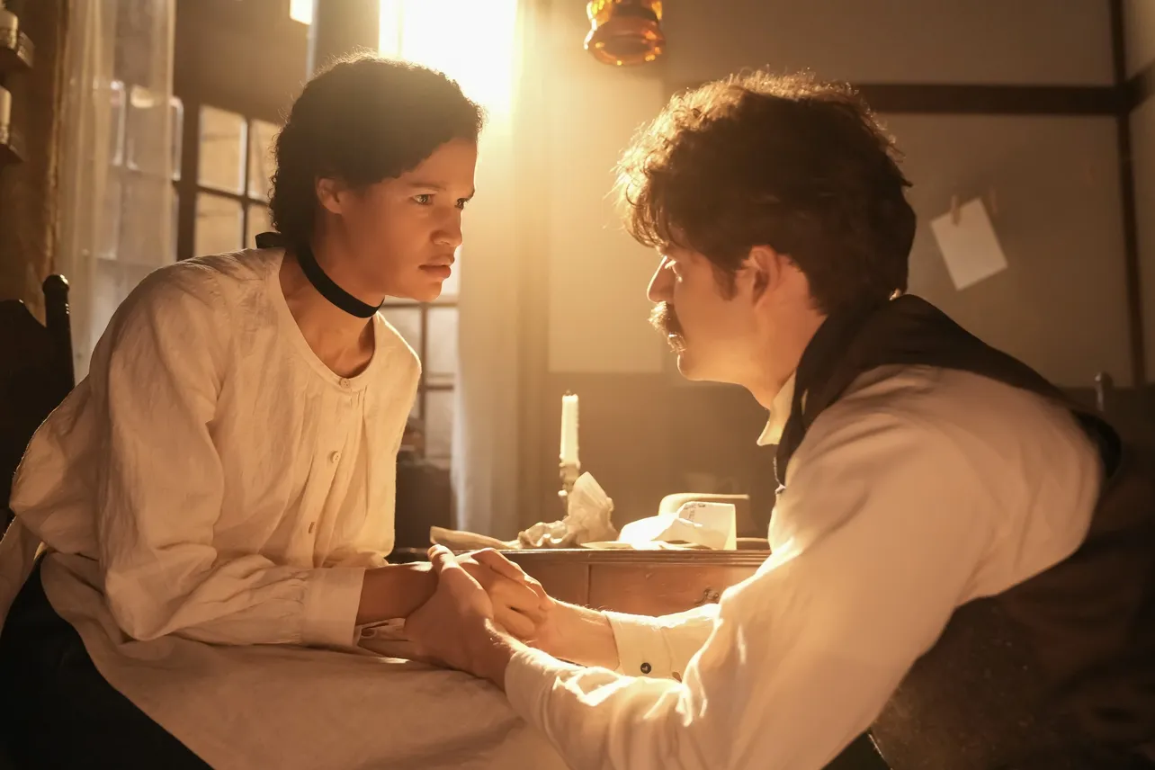 【写真】女性の手を握るヘブン(トミー・バストウ)