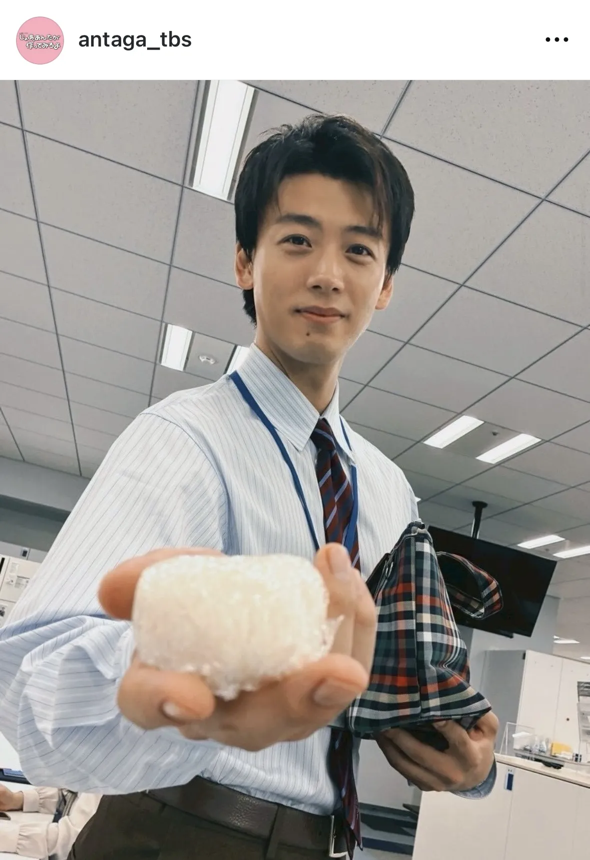 竹内涼真が優しくほほ笑みながら、おにぎりを差し出すショット