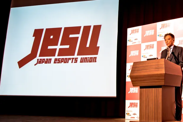 「日本eスポーツ連合」ロゴと代表理事の岡村秀樹氏