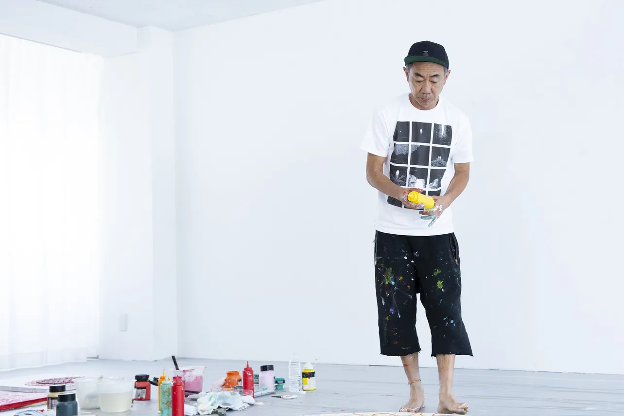 「白の美術館」で新作アートを制作する木梨憲武。今回は、ケチャップなどを入れる容器に絵の具を入れて吹き付ける、オリジナルの画法も披露