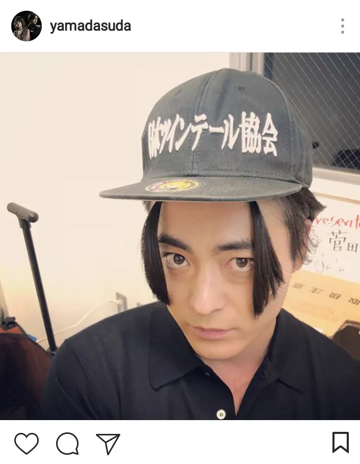 「日本ツインテール協会」と書かれた帽子をかぶりポーズを取る謎の山田孝之