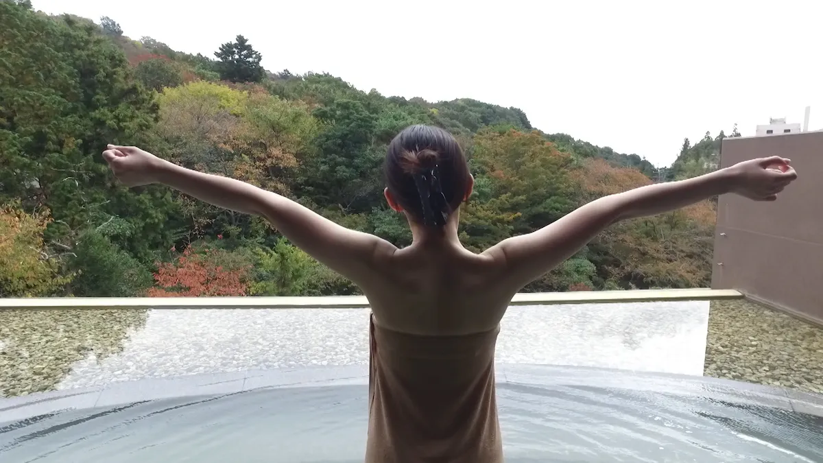 【写真を見る】開放的な露天風呂を楽しむ旅人・倉澤映枝の美背中も！