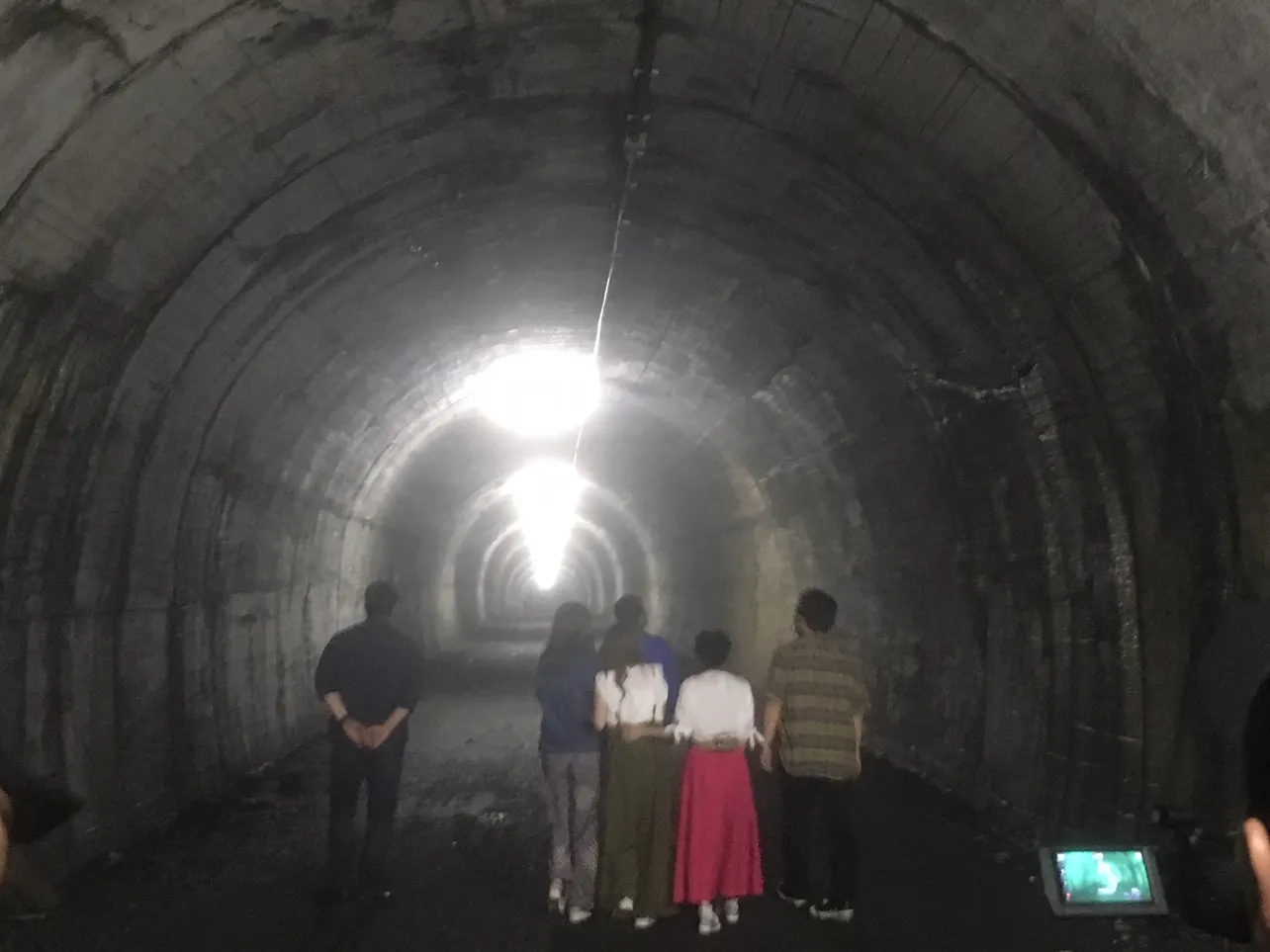 【写真を見る】薄暗いトンネル、身を寄せ合って歩いて行く一行