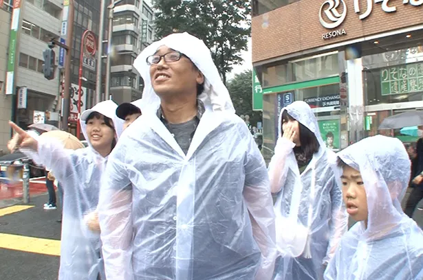 【写真を見る】雨の中、渋谷へとやって来た大家族