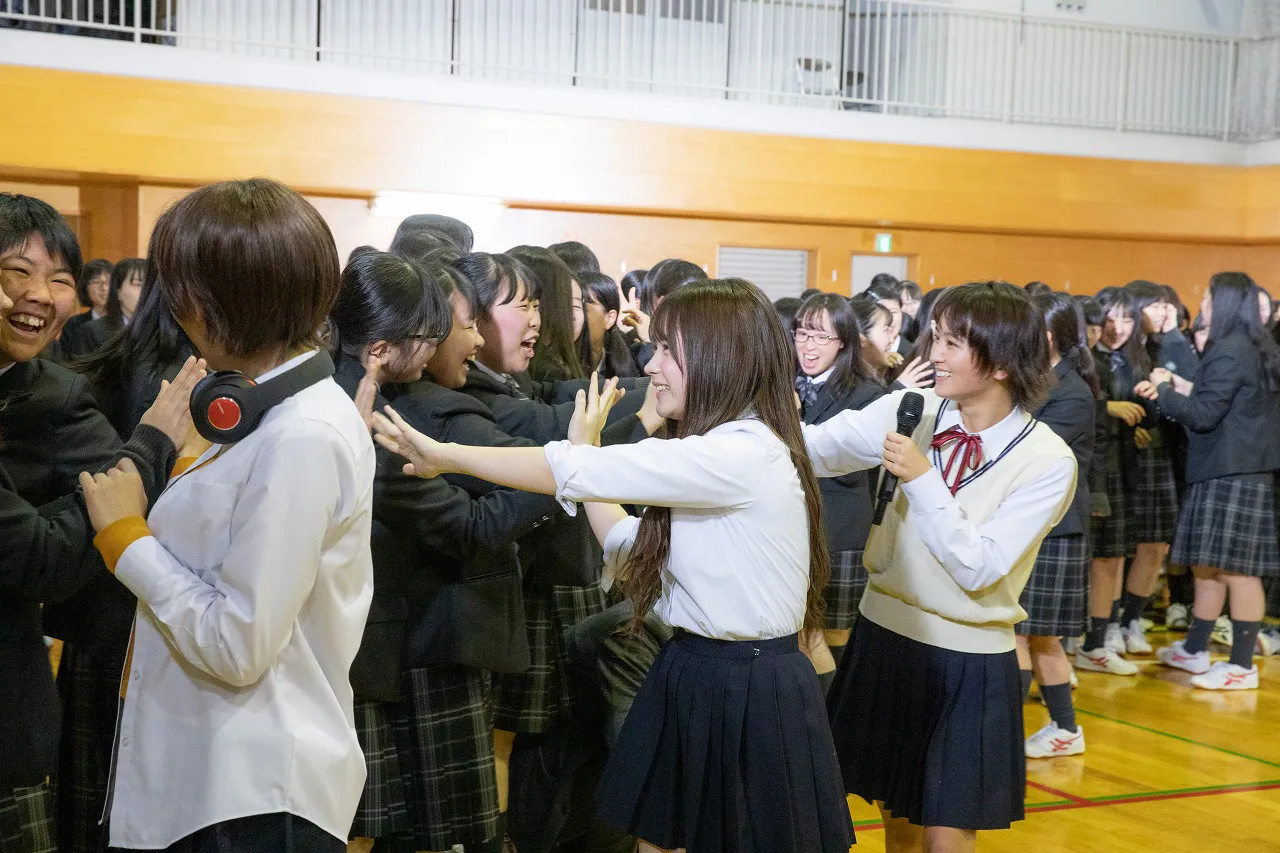蒲田女子高等学校の生徒とハイタッチする出演者