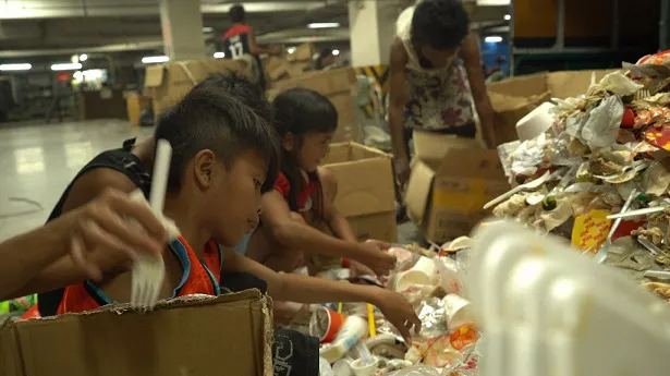 ショッピングモールのゴミ捨て場で残飯を集める少年少女