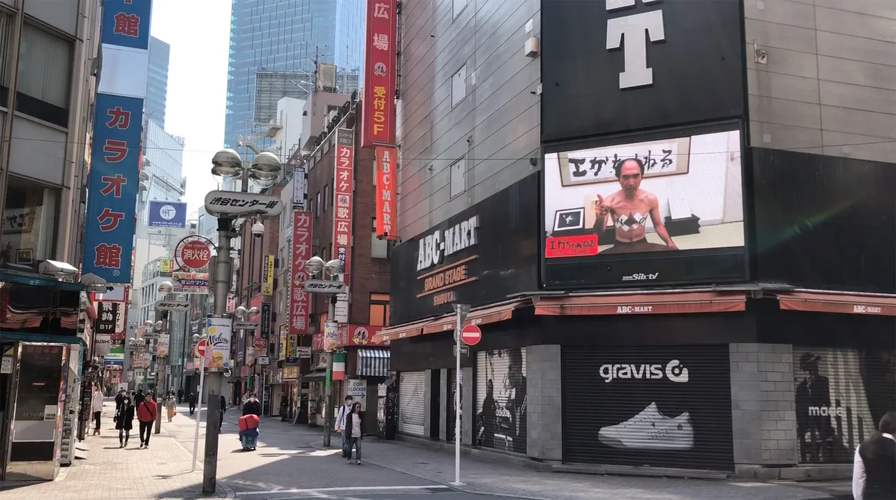 【写真を見る】実際に江頭の動画が放映されている渋谷センター街の様子　人はまばらに見える