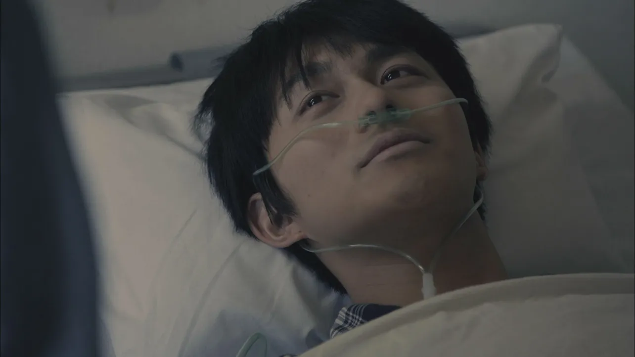 【写真を見る】ベッドに横たわり重い心臓病の患者を演じる小林豊