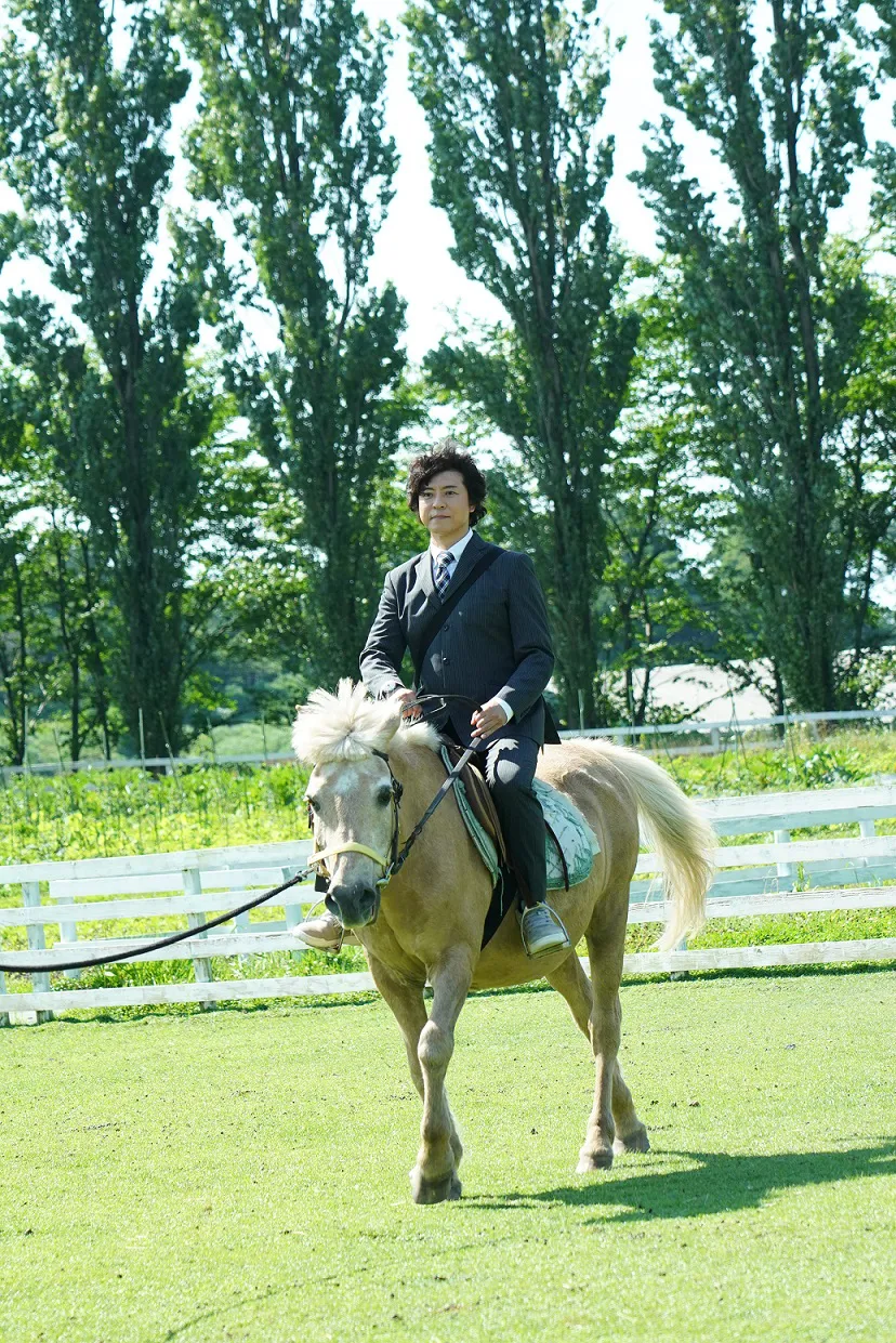 【写真を見る】スーツにスニーカーという“糸村スタイル”で乗馬に挑戦した上川隆也