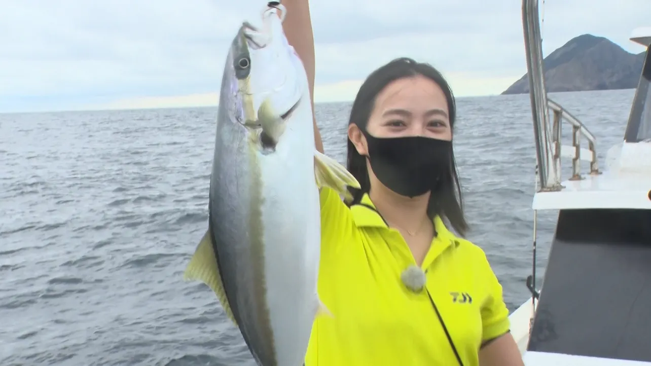 釣りあげた魚に笑顔を見せる矢野由希子