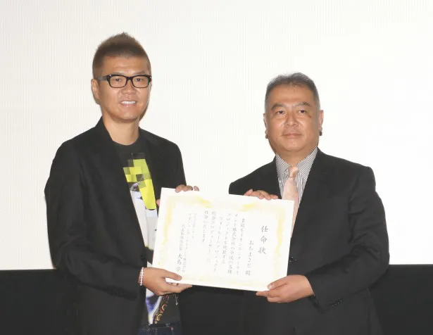 大島社長(写真右)よりウォールームプロジェクトの総合プロデューサーに任命されたおちまさと(写真左)