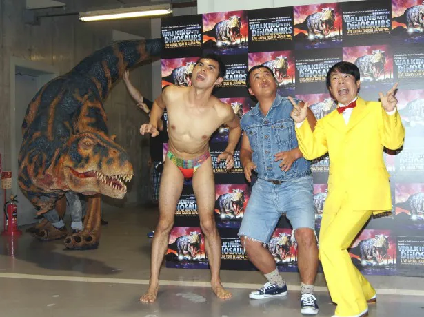 【写真】能天気にポーズをとる三人の背後に恐竜が忍び寄る