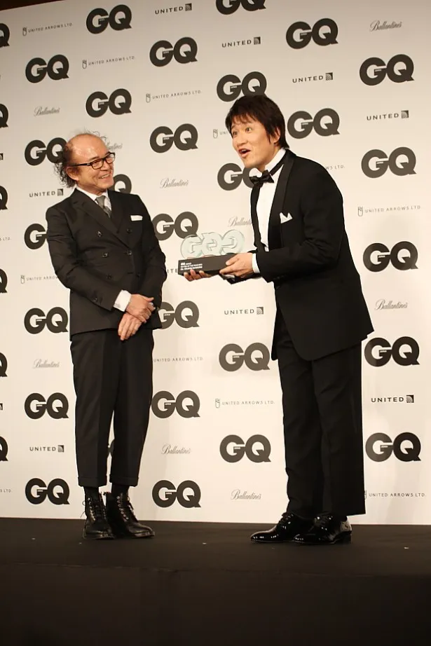 「GQ」編集長・鈴木正文(左)に「GQ Men of the Year」のトロフィーを渡される林修