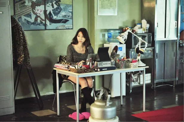 小泉麻耶演じるメグミは、受付嬢をしながら定時後は他の仕事もしている