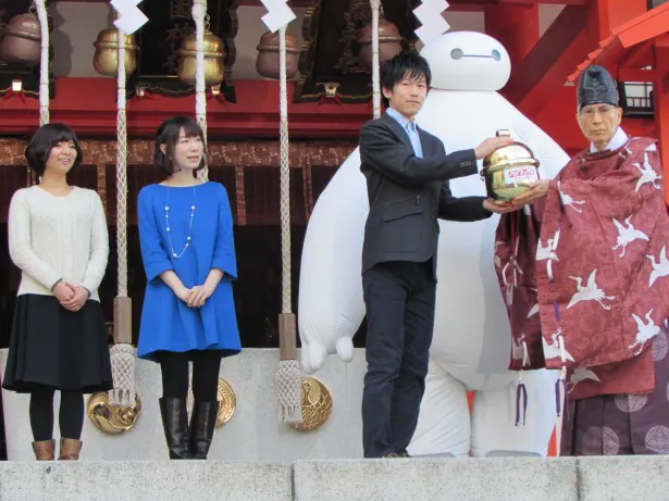 映画「ベイマックス」のイベントで鈴を奉納する(左から)山根舞、浅野真澄、本城雄太郎のキャスト陣とベイマックス、鈴を受け取る花園神社の宮司・片山文彦氏