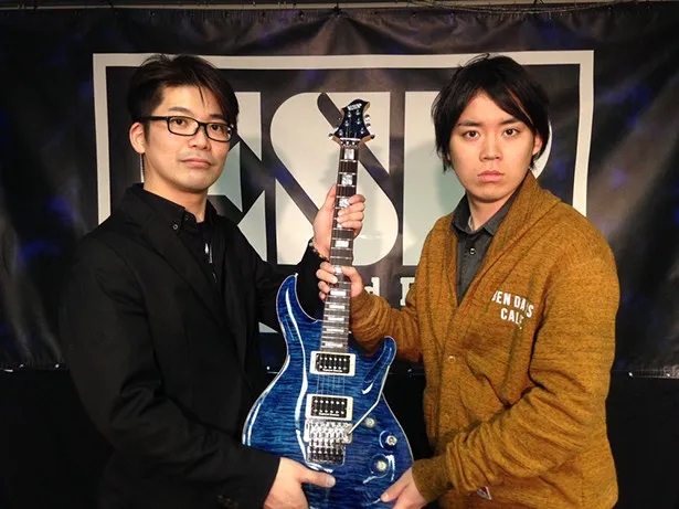 【写真を見る】世界的なギターメーカー「ESP」の担当者からギターを受け取る佐藤(右)