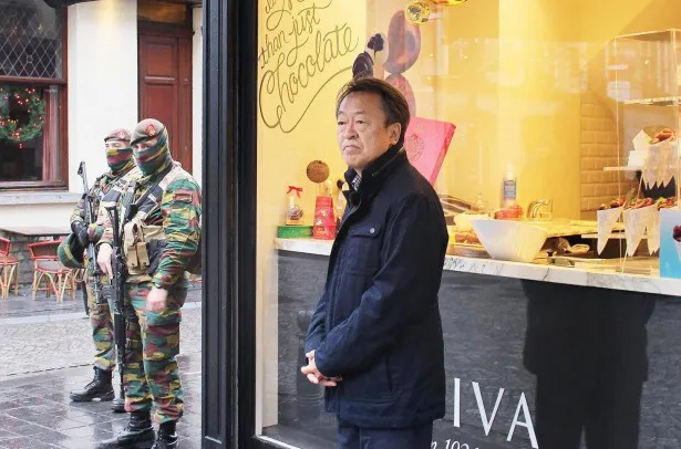 【写真を見る】ベルギーの有名チョコレート店の前で撮影中、武装した兵士が池上の横に…