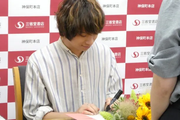 イベントに参加したファンにサインをして本を手渡す尾崎