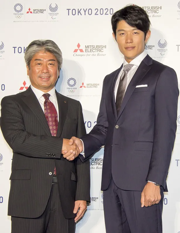 自身もバスケットボールで活躍していたという鈴木亮平は身長186cm。三菱電機株式会社関邦彦宣伝部長と握手