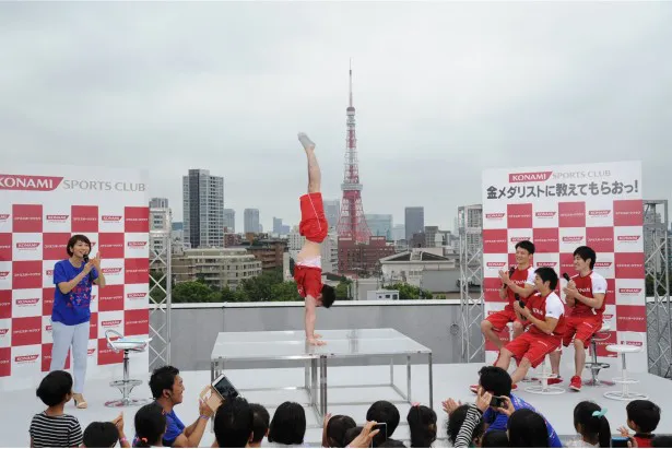 背後に見える東京タワーとも並び立つ見事な倒立に子供たちも仲間たちも驚く