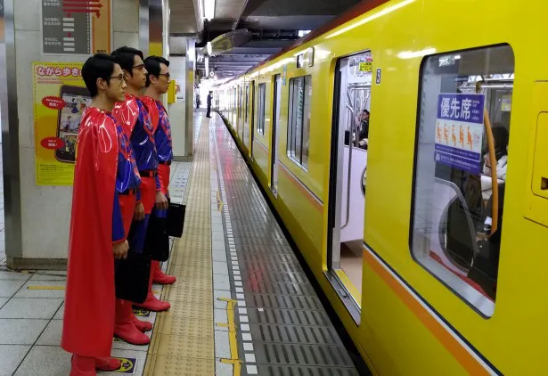 【写真を見る】スーパースーツで空を飛べるはずが、まさかの電車移動!?